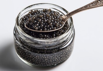 A small glass jar brimming with dark, glistening caviar; a tarnished silver spoon rests inside, laden with the delicacy