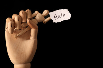 Paper piece with word HELP, wooden mannequin and hand on dark background. Domestic violence concept