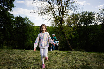Child running joyfully in a grassy clearing surrounded by lush green trees