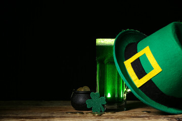 Glass of green beer with clover leaf, Leprechaun's hat and pot full of coins on black background....