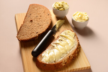 Wooden board with bread slices and bowls of fresh butter on brown background