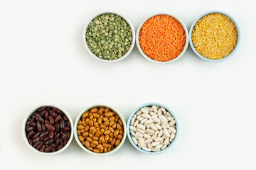 Various types of beans and lenties  in multi-colored round ceramic bowls, isolated. The concept of healthy eating and healthy living.