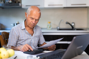 Senior man calculates profits and losses of online trading on calculator