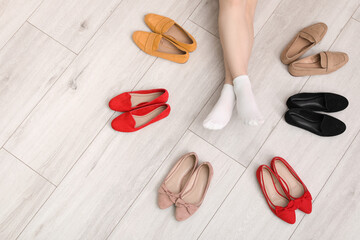Woman's legs in socks among shoes on white wooden background