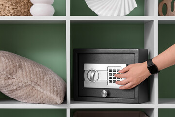 Woman opening safe on shelf near green wall, closeup