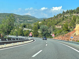 A car driving on a highway through a scenic mountain landscape.