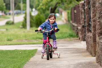 Happy child riding bicycle on sidewalk in suburban neighborhood