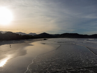 Fototapeta premium beautiful reddish sunrise on the beach with small waves and mountain horizon