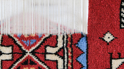 Manufacturing process, weaving of a traditional wool oriental red carpet with an intricate floral...