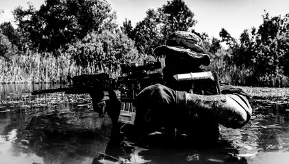 Silhouette of a soldier submerged in water, holding a rifle with foliage and trees in the background under a clear sky.