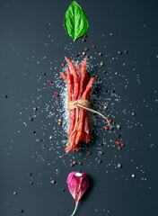 Kabanos meat sausages on a dark background with garlic, basil, salt and spices isolated