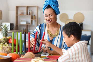 African-American mother with her son and candles having dinner at home. Kwanzaa celebration