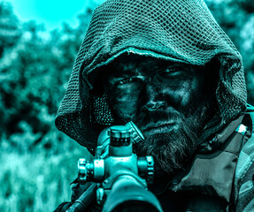 Intense sniper with a hood and camouflage face paint aiming a rifle, set against a blurred natural background with a blue color tone.