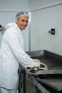Senior male wearing hairnet gloves handling metal component on table in processing room, copy space