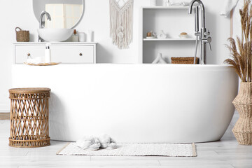 Soft slippers on rug near bathtub in stylish bathroom