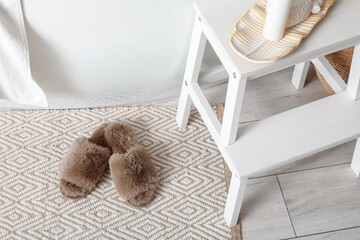 Soft slippers on rug near bathtub in bathroom, closeup