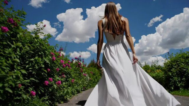 A beautiful woman in a white dress tanding on a path towards the clouds
