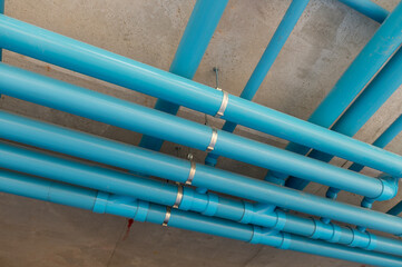 Organized plumbing system with metal brackets securing the pipes to a concrete ceiling