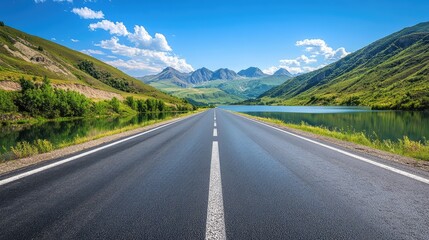 Fototapeta premium Scenic Open Road Surrounded by Majestic Mountains and Reflective Lake Under a Bright Blue Sky with Soft Clouds in the Background