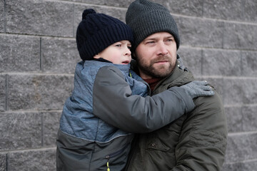 Father and son walking down on sidewalk together. Portrait of a handsome middle-aged man with...