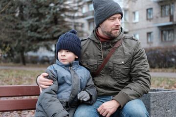 Father and son walking down on sidewalk together. Portrait of a handsome middle-aged man with...