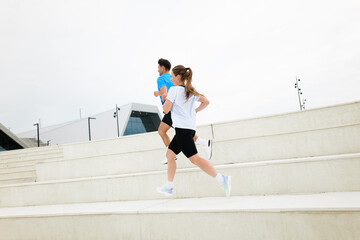 Energetic Joggers Ascend Modern Stairs During an Overcast Day in a Bustling Urban Environment