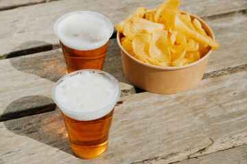 cups of beer and potato chips on a weathered dock