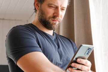 Man using his cellphone. Handsome guy use mobile phone at home. Male browses social networks, gaming, does shopping online, chats with friends, writes or reads messages. Close up. 4k video footage