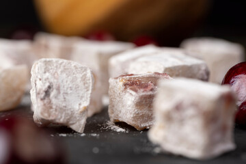 Turkish delight with cherry slices on a black slate board , cubes of sweet Turkish delight with...