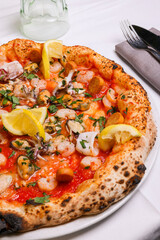 Pizza tradizionale napoletana con sugo di pomodoro, frutti di mare, gamberi, prezzemolo e limone fresco servita in una pizzeria