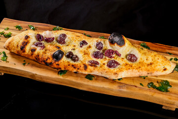Pizza tradizionale napoletana ripiena di scarole, provola, acciughe, olive e noci servita su un...