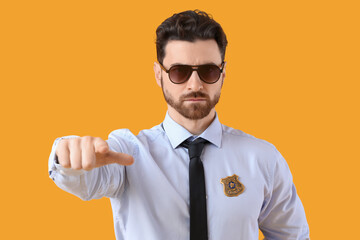 Male police officer with badge pointing at viewer on yellow background