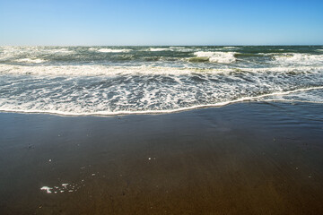 A sea storm in shallow water. Foamy waves and lots of quivering foam on the shore. Sakhalin, Sea of Japan