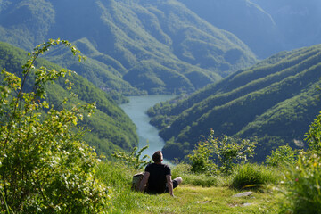 Man sitting and relaxing with view over river valley and mountains in Apuan Alps Regional Natural Park, Tuscany, Italy