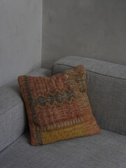 Close-up of decorative ethnic pillow with colorful woven pattern on modern gray sofa. Editorial use...