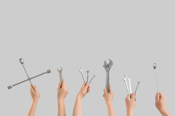 Many hands with wrenches on light background