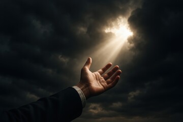 Hope emerges from darkness as hands reach towards a ray of light breaking through ominous clouds