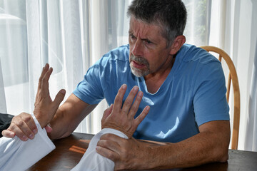 Obraz premium Medical staff abuse. Man threatening behaviour towards a doctor. Angry and violent patient grabs the wrists of the physician. Zero tolerance. 