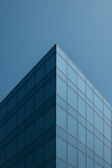 Fototapeta premium Minimal glass office building corner against clear blue sky, urban architecture 