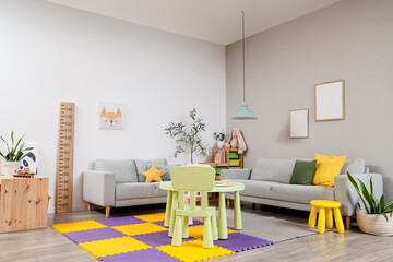 Interior of modern room with sofas, children's table, wooden stadiometer and toys on shelves