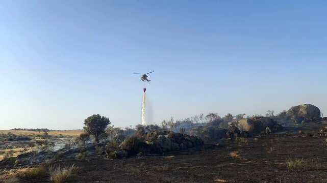 Helic&oacute;ptero de incendios trabajando sobre sona quemada enfriando la zona