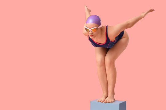 Female swimmer in start position on pink  background