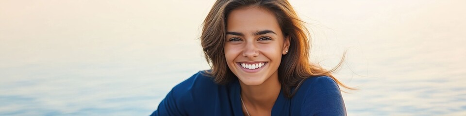 Smiling young hispanic woman by the sea at sunset