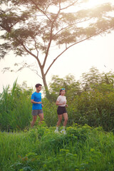 Fototapeta premium Asian Couple Jogging Together on Trail Through Lush Green Countryside