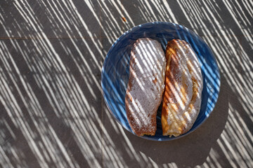 Fragrant and soft brioche roll filled with custard cream, topped with powdered sugar. Buns in the ceramics bowl in sunlight shadows. Remembering breakfast.