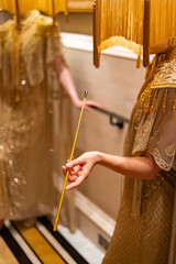 A surreal and theatrical figure stands in a gilded vintage gown and ornate lampshade headpiece,...