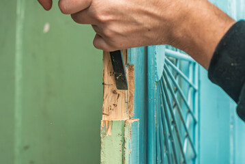 Closeup photo of man working with chisel to install new door lock. Installing door lock, hands...