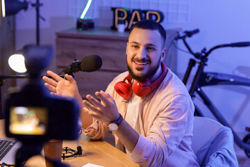 Young man recording podcast at table in studio