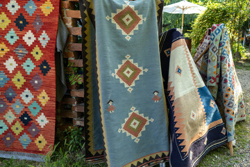 Colorful traditional kilim rugs on display at an outdoor market.