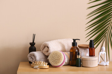 Composition with spa accessories, cosmetic products and palm leaf on wooden table near color wall